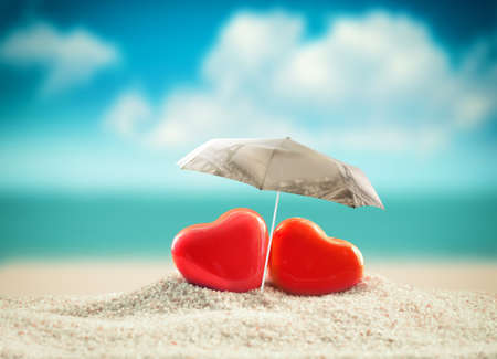 Two hearts under umbrella on the summer beach. Valentines day.の写真素材