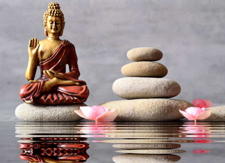 Buddha is sitting in ZEN garden with flower and balance stones.の写真素材