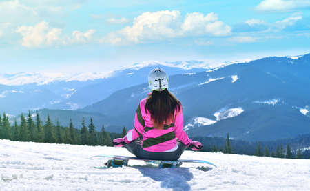 The young beautiful woman in mountains has a rest in the winter at the weekend, meditation, yogaの写真素材