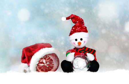 cheerful snowman in santa hat on a snowy backgroundの写真素材
