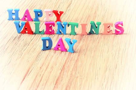 The words happy valentines day made with block wooden letters on light wooden background
