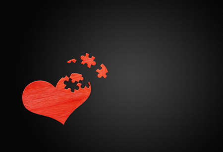 Red wooden puzzle heart on black wooden backgroundの写真素材
