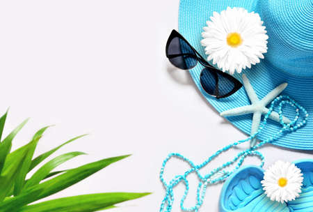 Green palm on white surface with beach items, top view.の写真素材