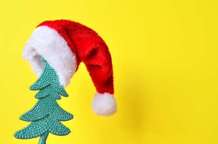 Christmas tree in Santa hat on yellow Christmas background.の写真素材