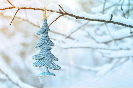 Abstract christmas tree, hanging on a snow-covered branch in the park. Happy New Year.の写真素材