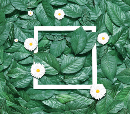 Creative layout made of flowers and leaves with paper frame. Flat lay. Eco nature concept.