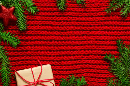 Christmas red knitted background with branch fir, stars, new year concept, giftの写真素材
