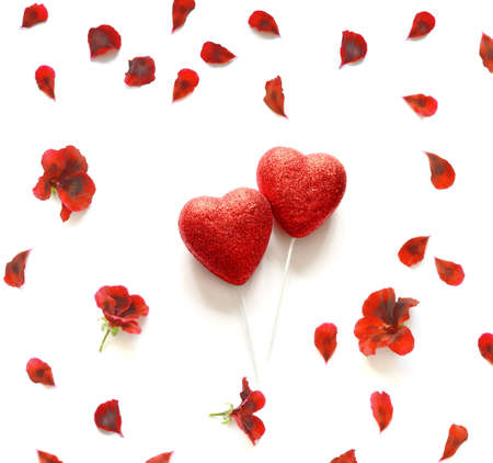 Two shiny red hearts on a white background, studded with flower petals. Valentine's Day.の写真素材