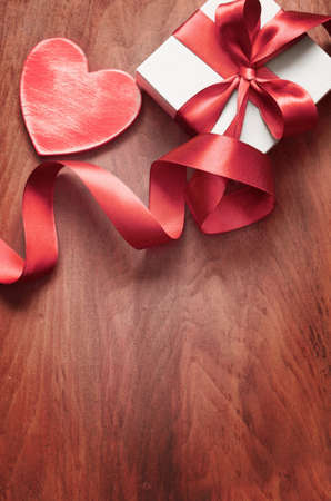 White gift box and red ribbon with tag on wood background with space. Vintage gift box on wooden board with space for text.の写真素材