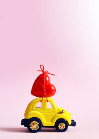 Little yellow car carries a red heart. The concept of Valentine Day.の写真素材