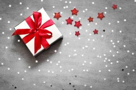 Gift box with red ribbon on grey background with star. Top view.の写真素材