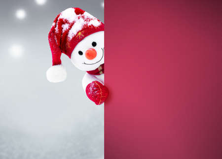 Little snowman in caps and scarfs on snow in the winter. Festive background with a funny snowman. Christmas card, copy space.の写真素材
