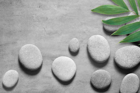 Flat lay composition with spa stones, green palm leaves on grey background.の写真素材
