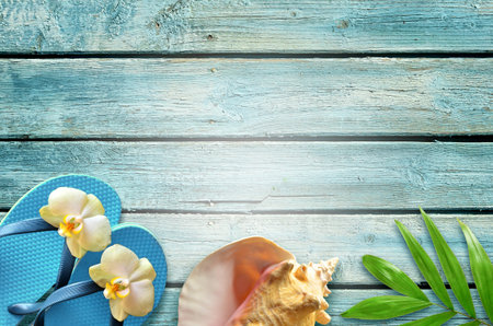 Summer flat lay background. Tropical palm leaves, flip flops and flower on old blue wooden...