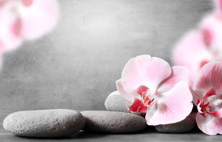 Spa stones and pink orchid on the grey background. Spa concept.の写真素材