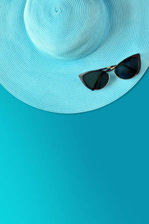 Summer hat with sunglasses. Top view, minimal concept over a blue backgroundの写真素材