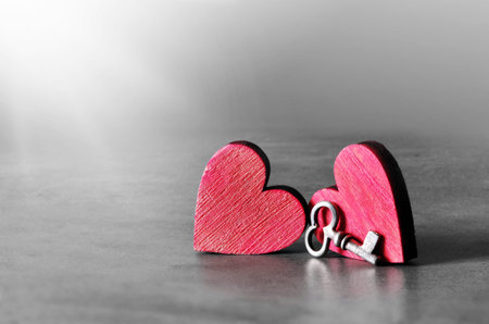 Silver key and red wooden hearts on gray background. Valentines Day. Holiday concept.