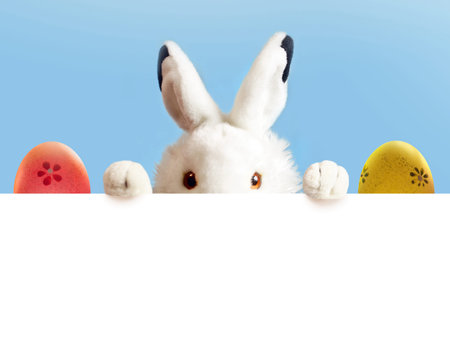 An Easter white bunny toy are two Easter color eggs on blue and white background.