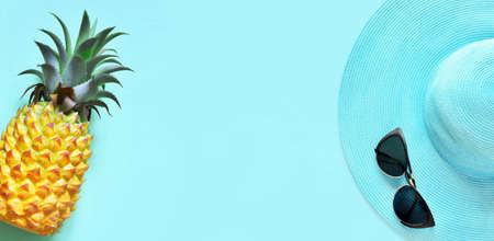 Yellow pineapple and blue hat with sunglasses on a blue background.の写真素材