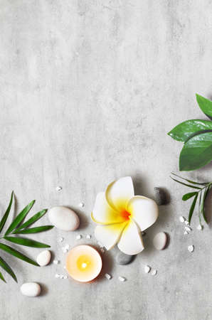 Spa concept on stone background, palm leaves, flower plumeria, candle and zen, gray stones, top view, copy space.の写真素材