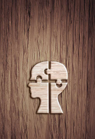 Human head silhouette with a jigsaw piece cut out on the wooden background, mental health symbol.の写真素材