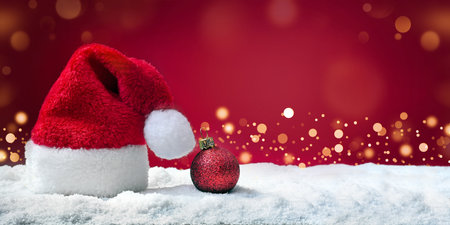 Santa hat on snow on red background, Christmas decoration. Holiday concept.の写真素材
