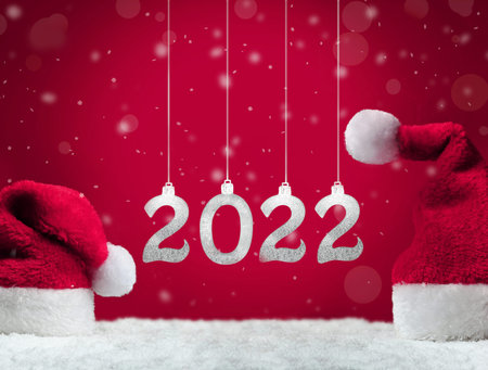 Santa hats on snow on red background, Christmas decoration. Christmas background. 2022.