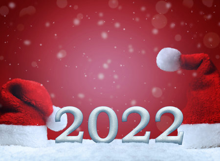 Santa hats on snow on red background, Christmas decoration. Holiday concept. 2022.の写真素材