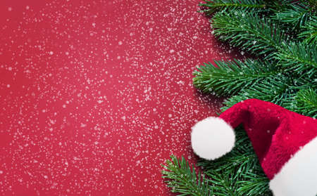 Red background with fir branches and Santa hat. Christmas decoration. Holiday concept.の写真素材