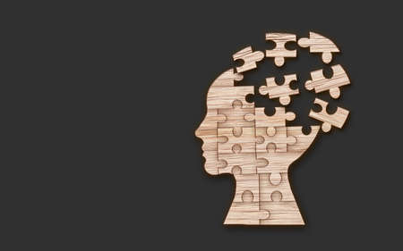 Mental health symbol. Human head silhouette with a puzzle cut out from wooden background.の写真素材