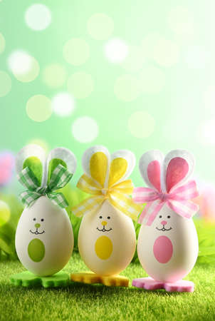 Funny easter eggs in the grass on blurred background. Happy Easter background. Easter compositions with cute rabbit eggs.の写真素材