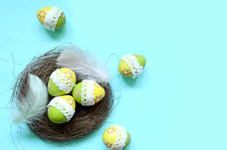 Easter eggs in a nest with feathers on a blue background. holiday concept.の写真素材