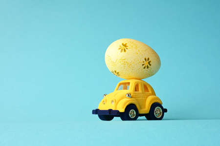 One Easter egg on a small car on a blue background. copyspace. Easter card.の写真素材