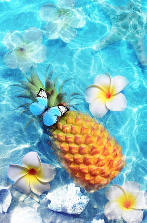 Yellow pineapple and white flowers on a blue water background. Exotic concept.の写真素材