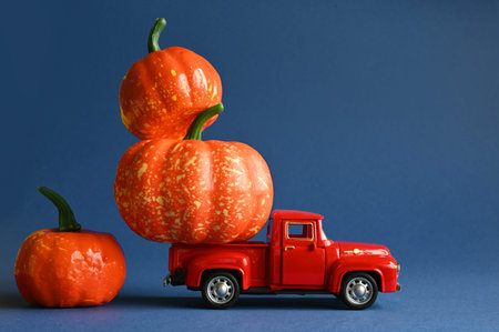 Retro truck with pumpkins and leaves on blue background. Concept of Thanksgiving day, Halloween and...