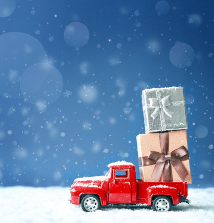 Christmas background with snow and retro red car with gift box. .Merry Christmas and happy New Year greeting winter card with copy-spaceの写真素材