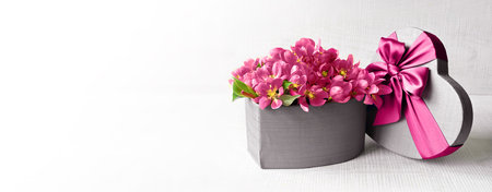 Valentines Day. Pink flowers in a grey box in the form of a heart on a white background. The concept of delivering flowers. floristry and flower shops.の写真素材