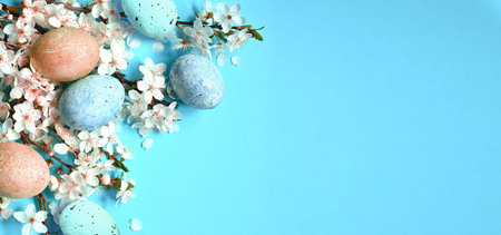 Easter eggs with spring blossom flowers on blue background. Colored Egg Holiday border