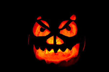 Lighting homemade carved Halloween pumpkin with black background
