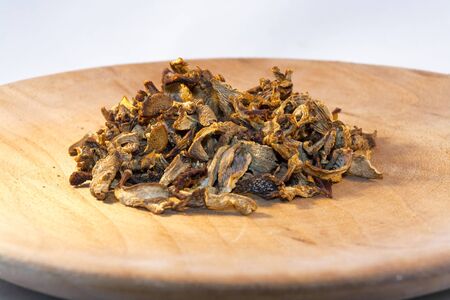 Heap of dried golden chanterelle (Cantharellus cibarius) on a wooden plateの写真素材
