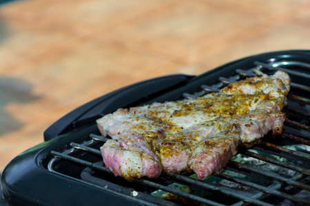 Baking pork meat on a barbecue in a gardenの写真素材