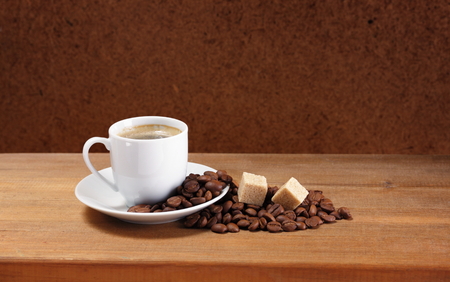 Coffee cup on saucer, beans and sugar on a wooden table  Dark background  の写真素材