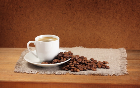 Coffee beans, cup, saucer and napkin on wooden table  Dark background の写真素材