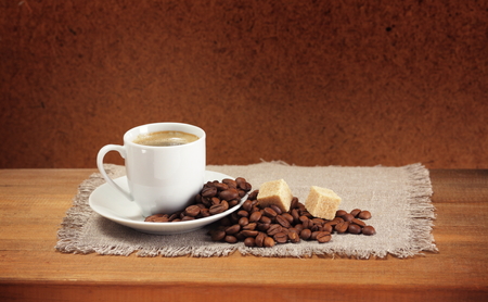 Coffee beans, cup, saucer, sugar, napkin on wooden table  Dark background の写真素材