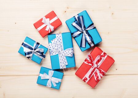 wrapped gift boxes with ribbon bows on wooden boardの写真素材
