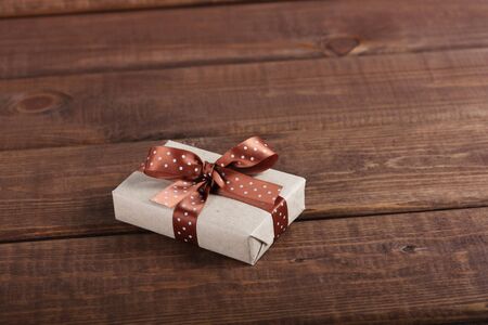 wrapped gift box with ribbon bow on dark wooden boardの写真素材