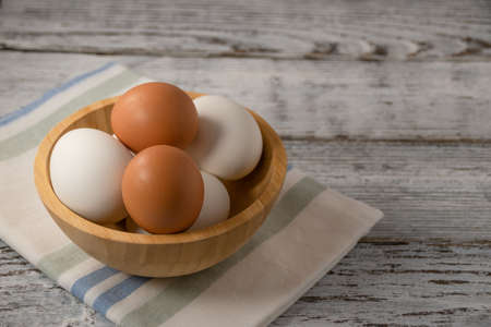 white and brown eggs on a wooden bowl on a napkinの写真素材