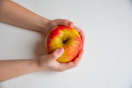 child's hands hold fresh appleの写真素材