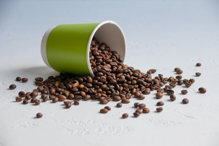 coffee beans spilled out of a green paper cup