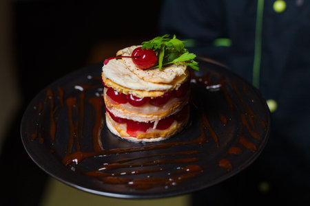 Dish from the chef salad with meat, cherry, sauce, parsley on a black plate Stock photo ID:...